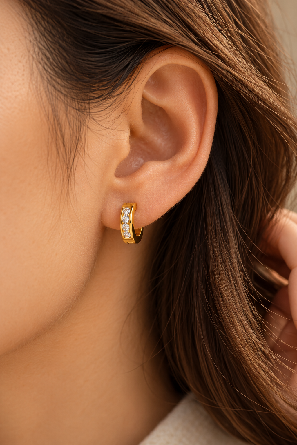 Gold tone stainless steel huggie earring set with cubic zirconia, worn in the ear