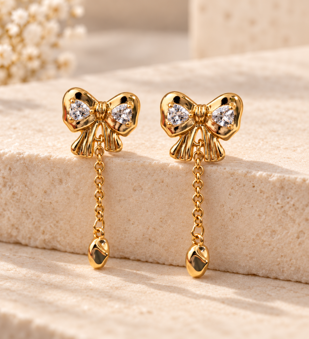 Gold tone bow chain drop earring with cubic zirconia, worn in the ear