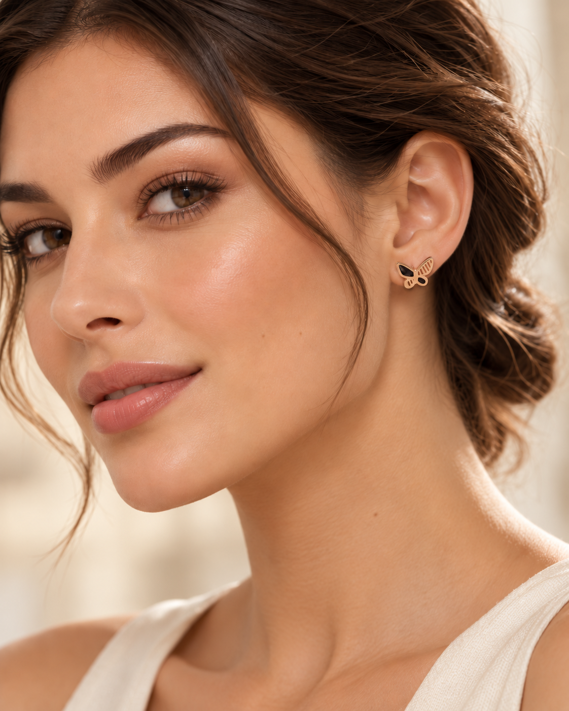 Gold tone butterfly stud earring with dark inlay worn in the ear