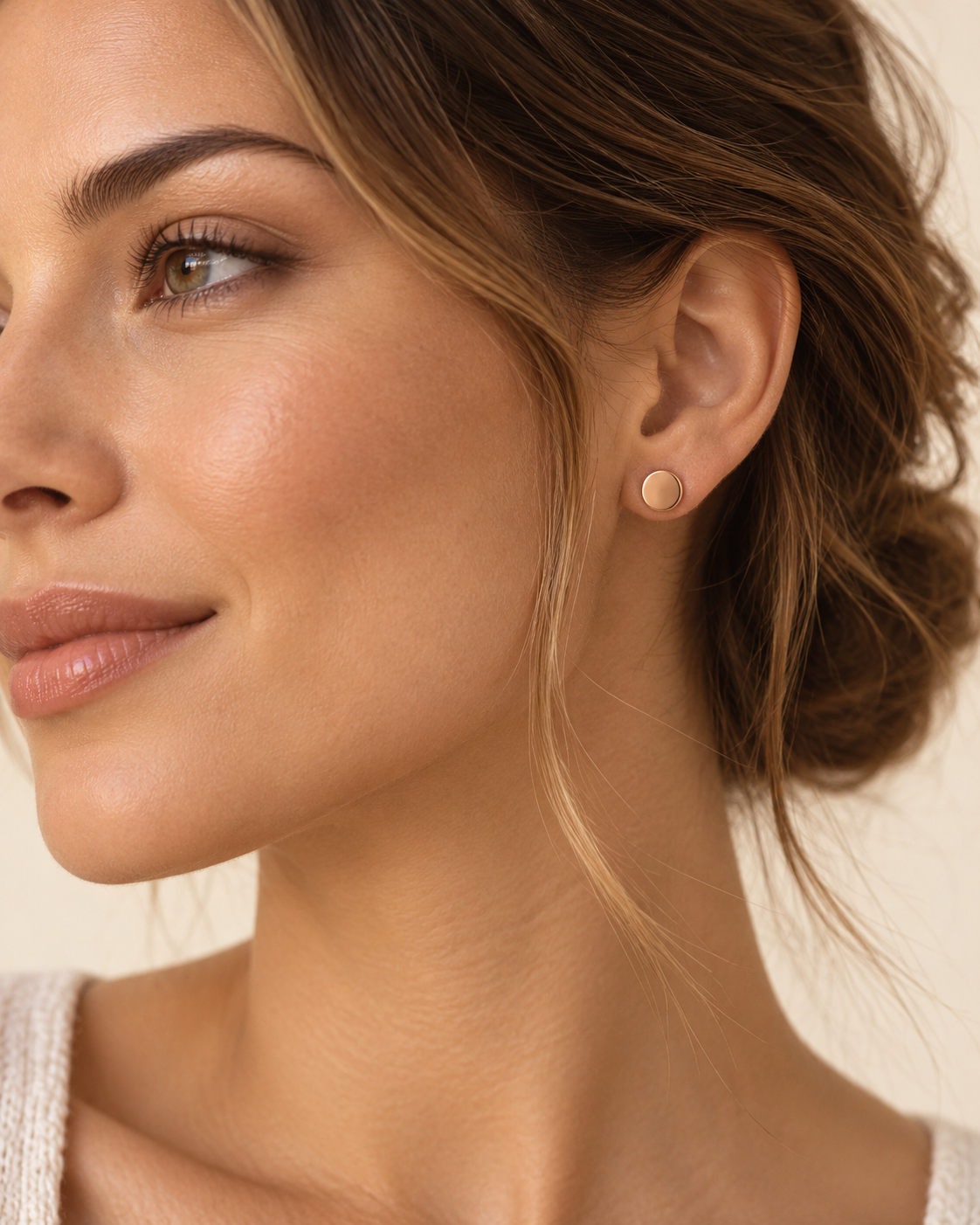 Gold tone disc stud earring worn in the ear